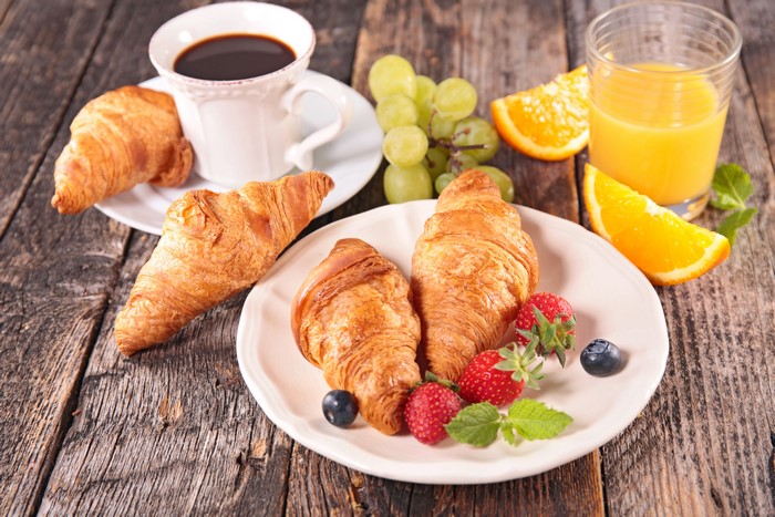 Breakfast with coffee, croissants, fruit, and orange juice