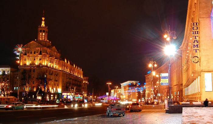 Night street view of a city with illuminated buildings and cars