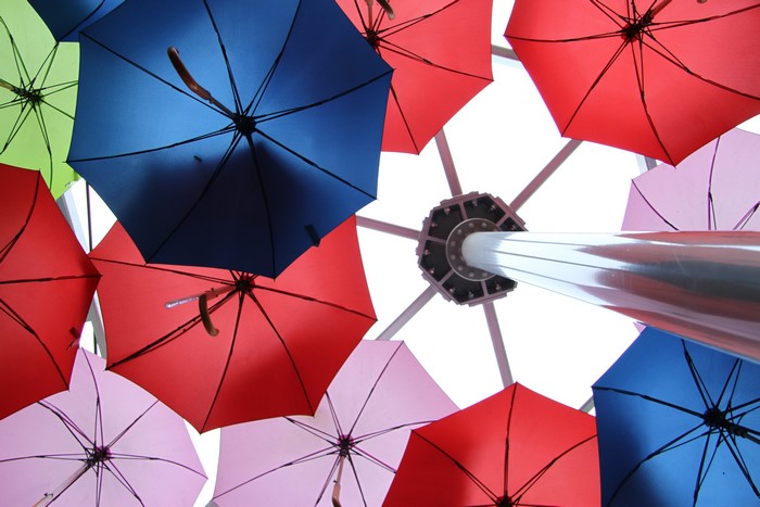 Many colorful umbrellas hanging from a ceiling structure