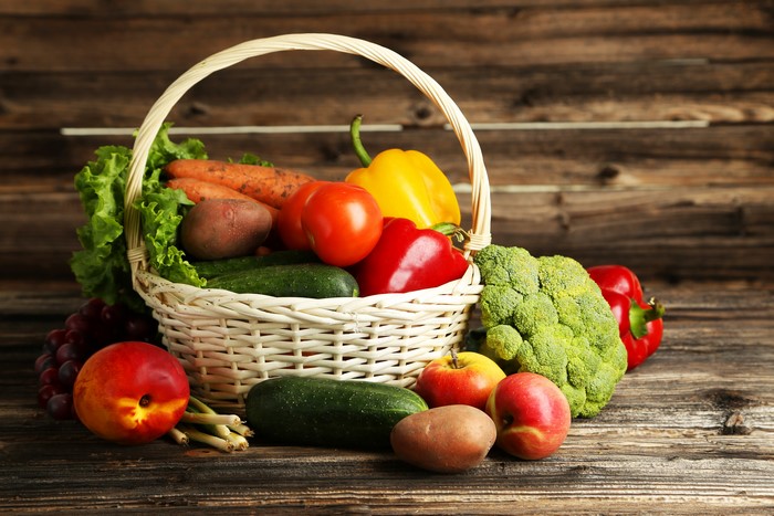 Basket of fresh vegetables and fruits on a wooden table