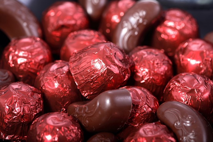 Many red wrapped chocolates and some plain chocolates