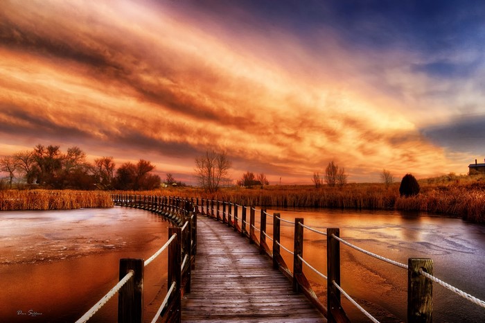 Wooden bridge over frozen river at sunset in Colorado