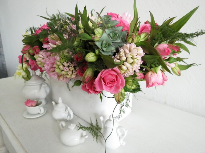 Floral arrangement with roses and hyacinths in a white vase with teacups