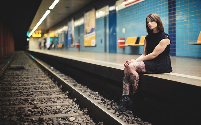 Woman with tattoos sitting on a subway platform