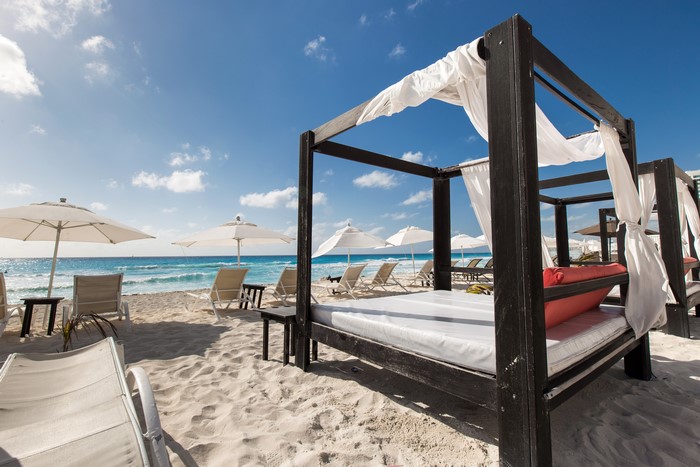 Beach with canopy beds, sunloungers, and umbrellas