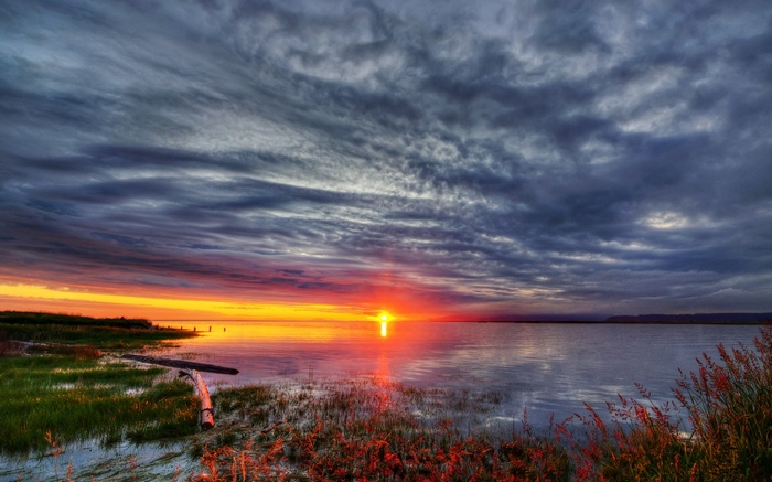 Sunset over a calm body of water with dramatic clouds