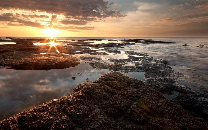 Sunset over rocky coastline with calm sea