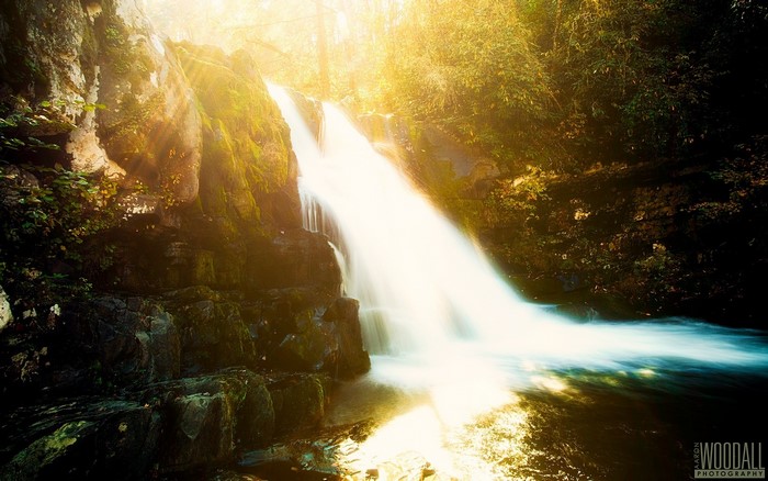 Waterfall with sun rays and rocks