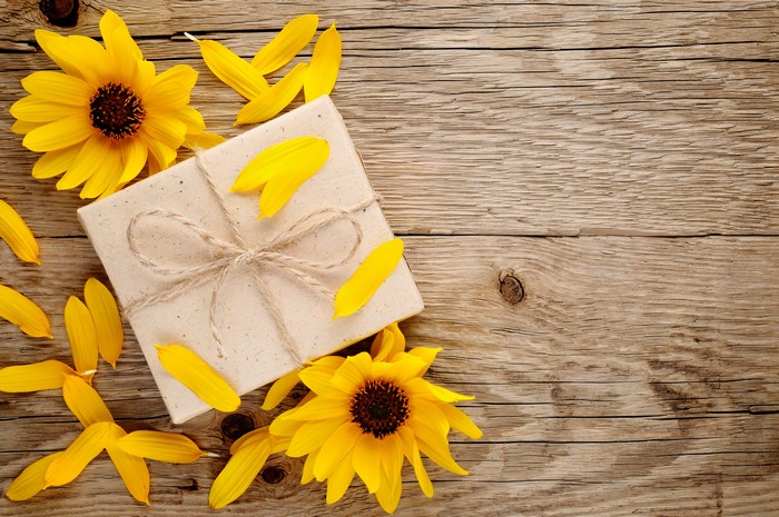 Gift box with sunflowers and petals on wood