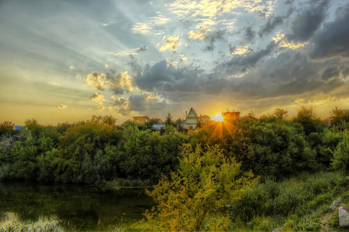 Sunset over a river with trees and houses in Russia