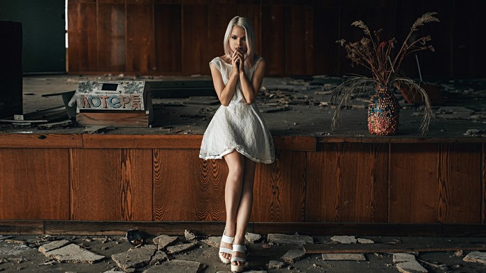 Blonde girl in white dress on stage with vase