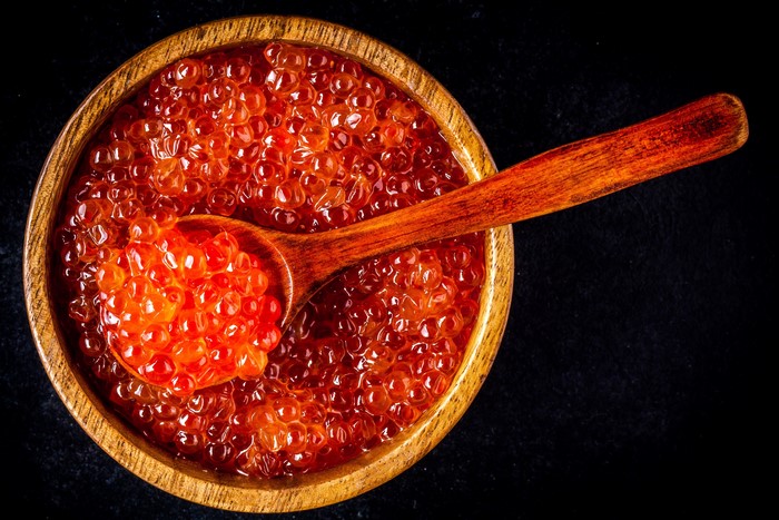Red caviar in a wooden bowl with a spoon