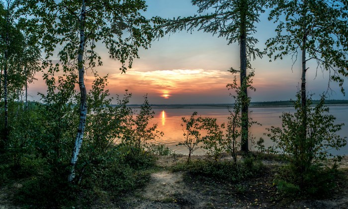 Sunset over a lake framed by trees