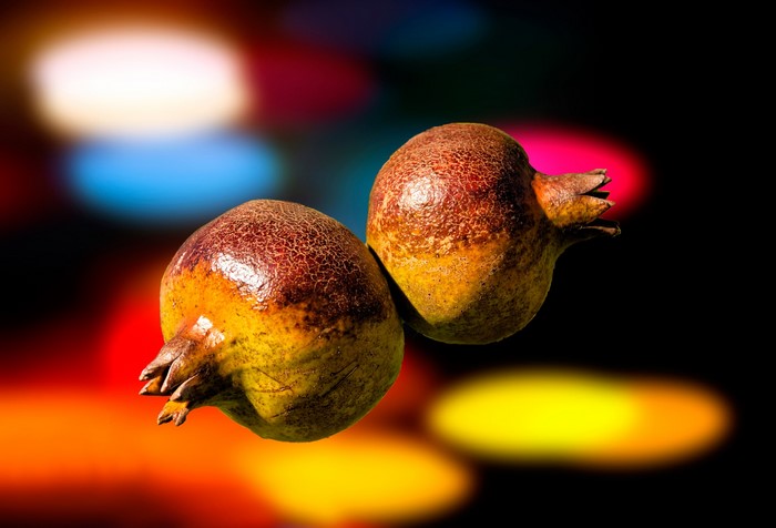 Two pomegranates on a colorful bokeh background