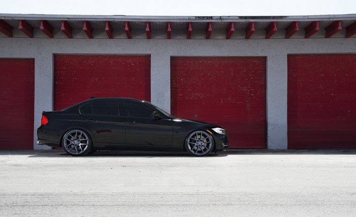 Black BMW E90 Sedan parked in front of a garage