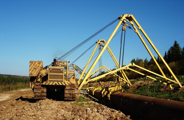Yellow pipelayer machine laying a large pipe