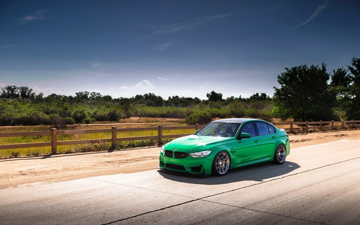 Green BMW M3 F80 on a road with a fence