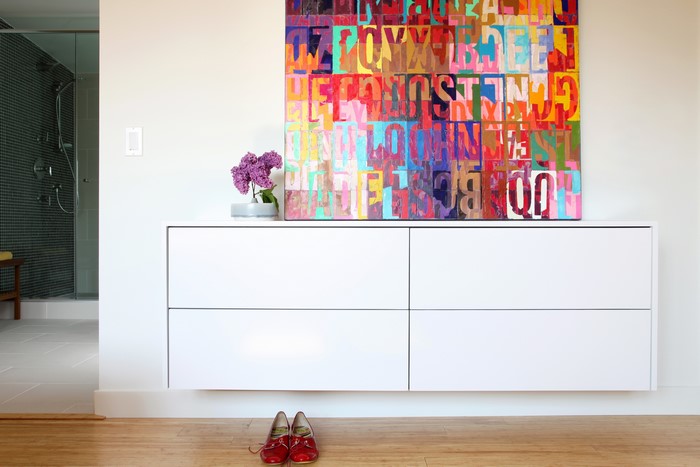 Colorful abstract art above a white dresser