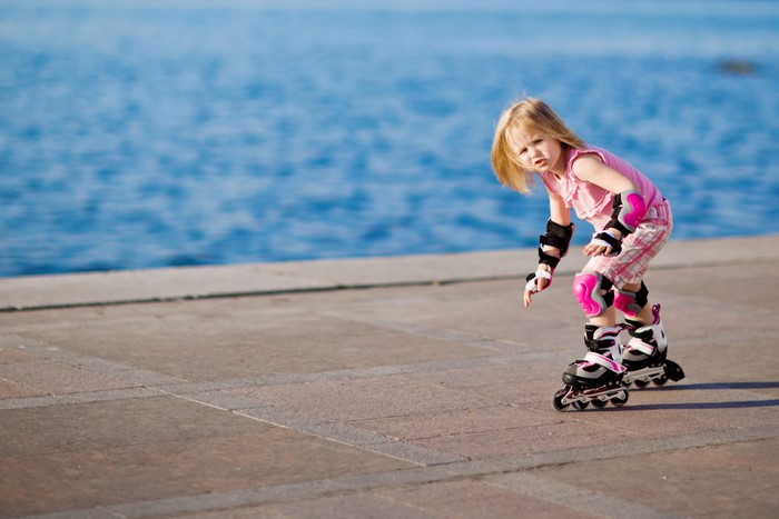 Little girl rollerblading by the water