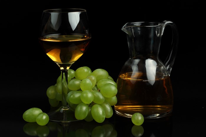 White wine in a glass and jug with green grapes
