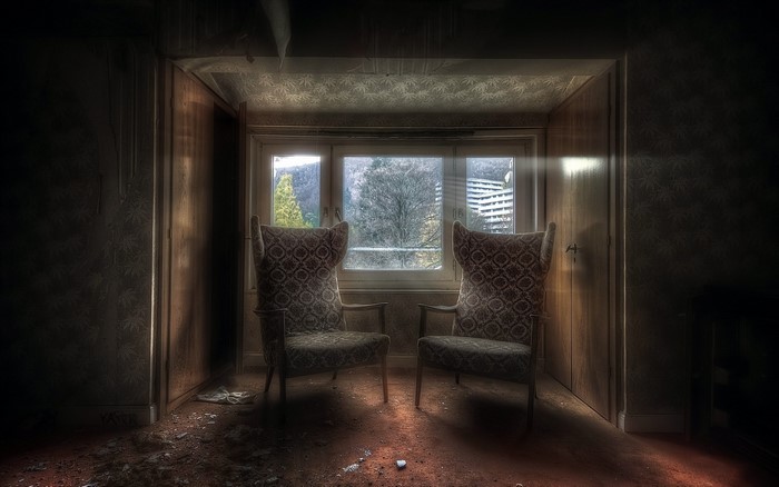Two armchairs in a derelict room by a window