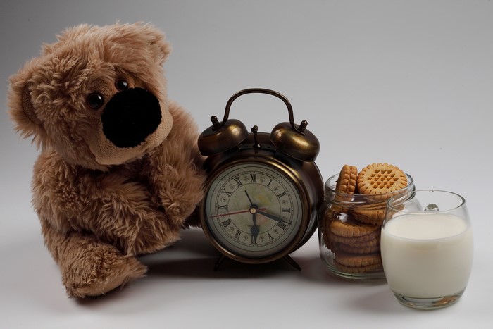 Teddy bear with alarm clock, cookies, and milk