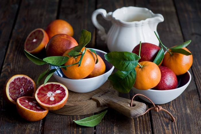 Blood oranges and tangerines with leaves and a pitcher