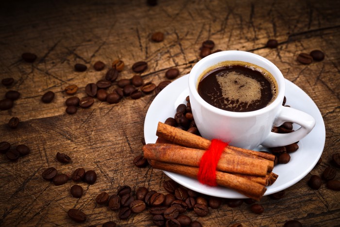 Coffee cup with cinnamon sticks and coffee beans