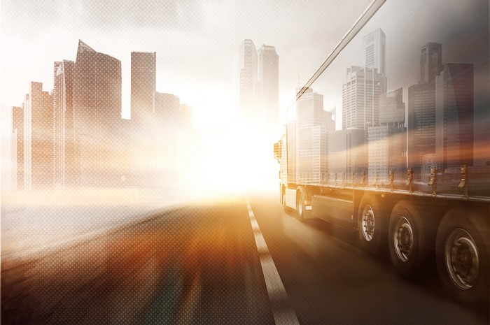 Truck driving on a road with city skyline
