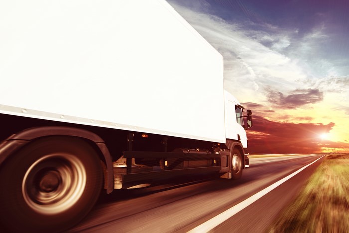 White truck driving on a road at sunset