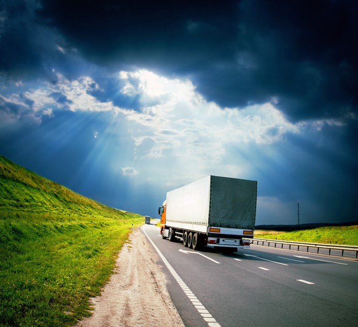 Truck driving on a highway under dramatic clouds