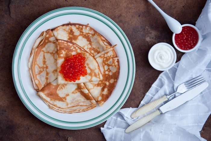 Pancakes with caviar, sour cream, and cutlery