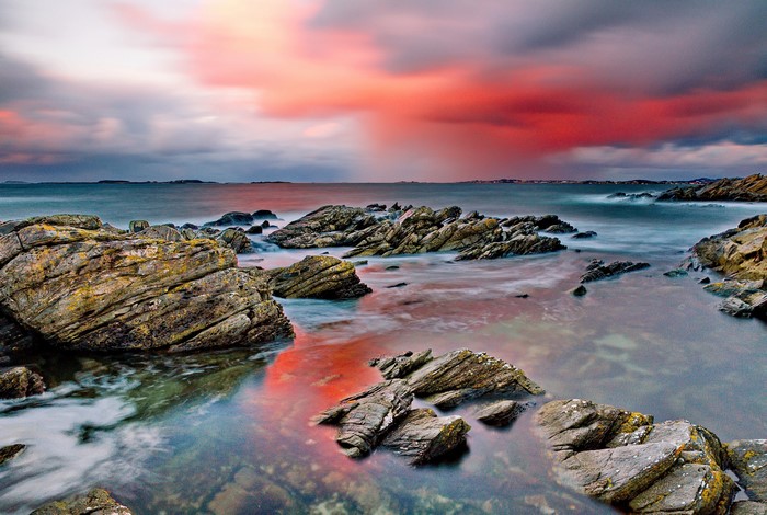 Rocky coastline with colorful sunset clouds over the sea