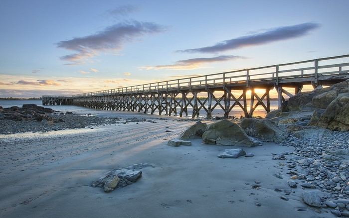Wooden pier over a rocky beach at sunset