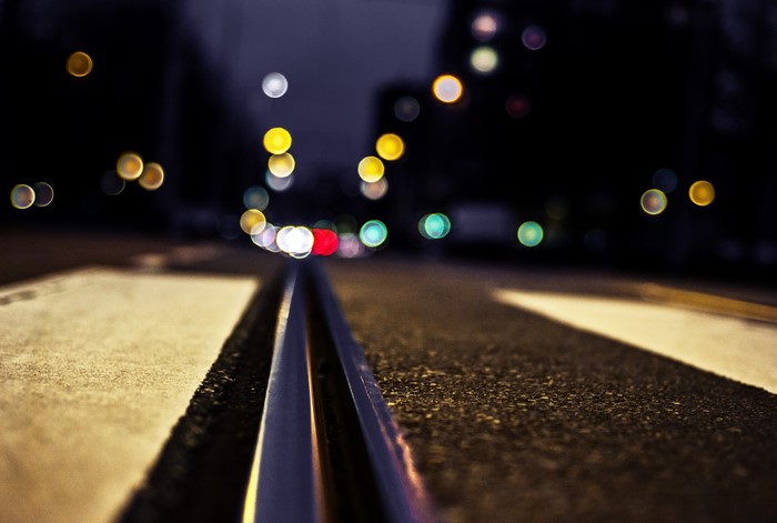Close-up of railroad tracks at night with bokeh lights