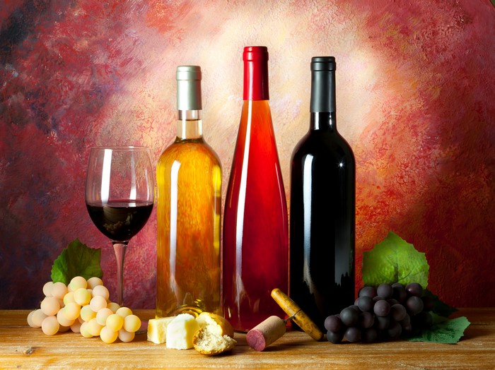 Wine bottles, glass, grapes, bread, and cheese