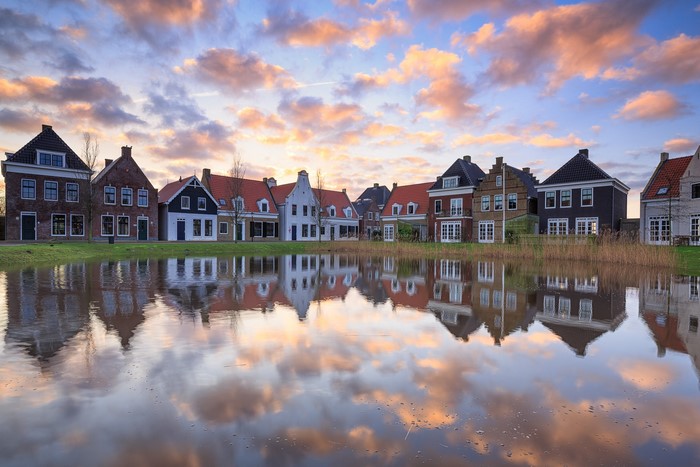 Row of Dutch houses reflected in water at sunset