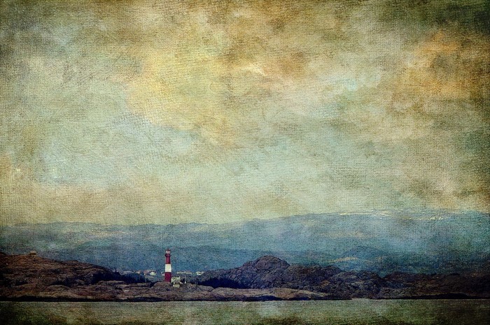 Lighthouse on a rocky shore with distant hills