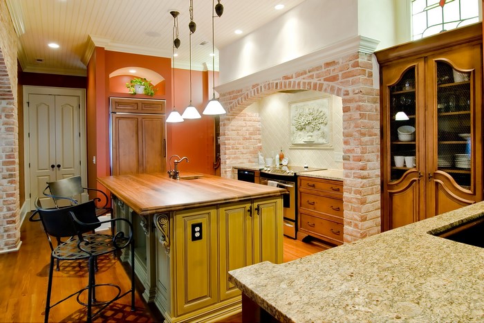 Kitchen with island, brick archway, and wooden cabinets