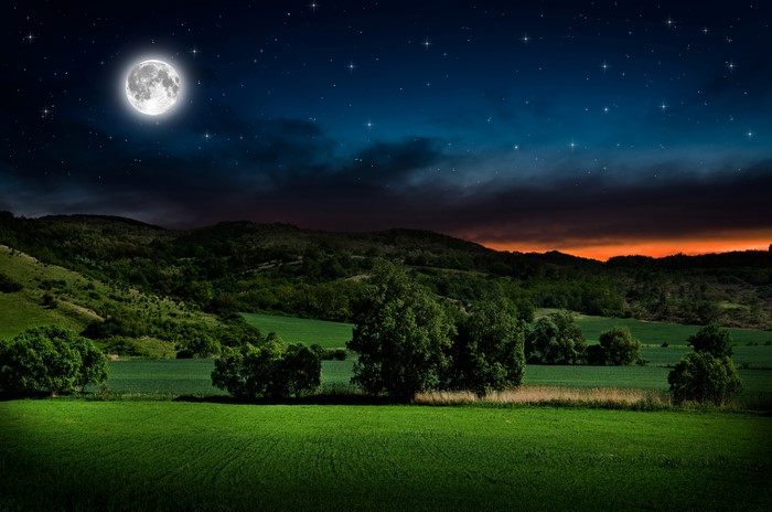 Night landscape with moon and stars over hills and fields