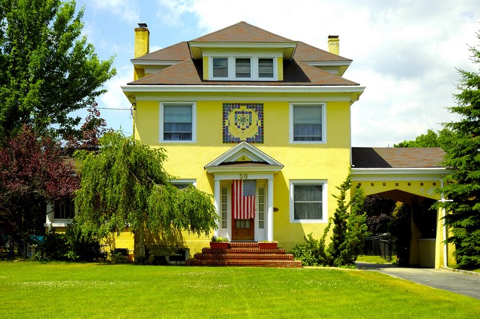 Yellow house with American flag and trees