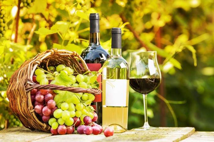 Wine bottles, grapes, and wine glass in a basket