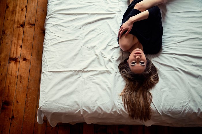 Woman with brown hair lying on a bed