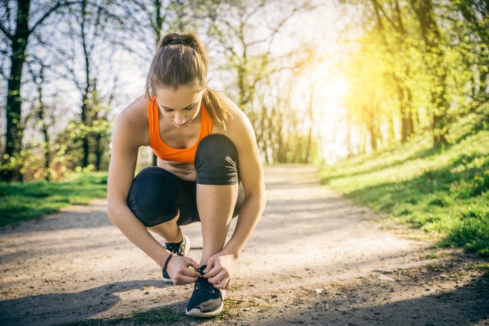 Woman tying running shoes on a path