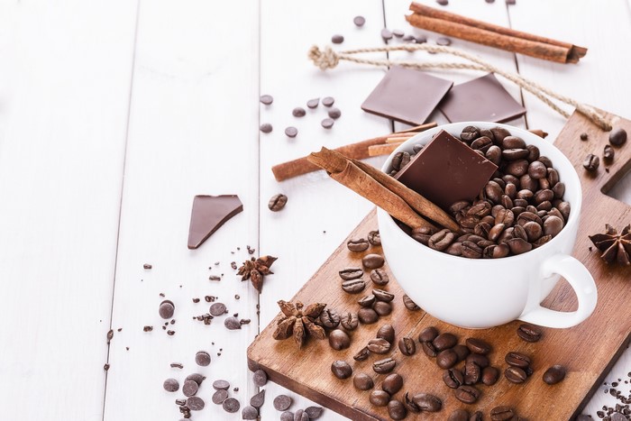 Coffee beans, chocolate, and cinnamon sticks in a cup