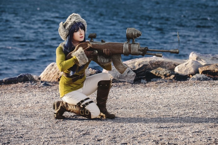 Woman in fur hat with assault rifle on coast