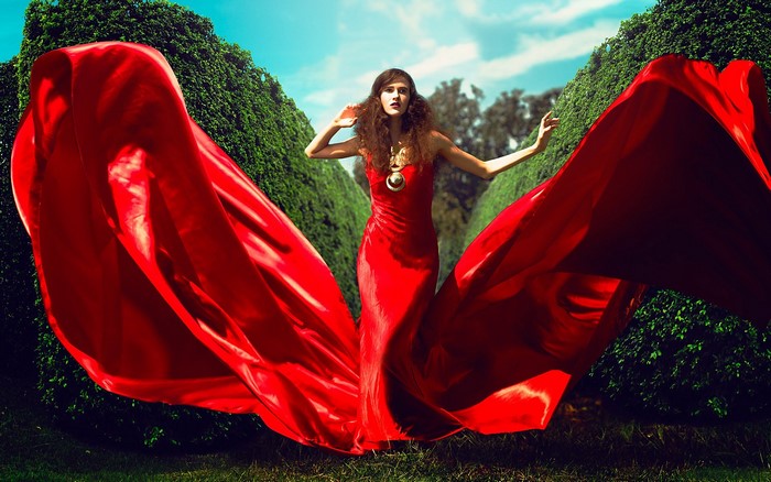 Woman in red dress with flowing fabric in garden