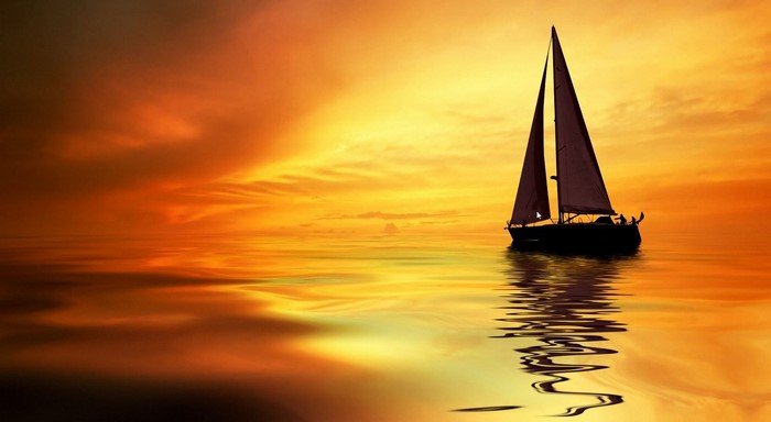 Sailboat silhouetted against a vibrant sunset over the ocean