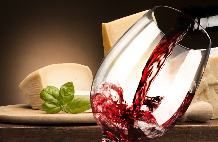 Red wine pouring into a glass with cheese and basil