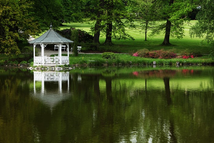White gazebo by a lake in a park